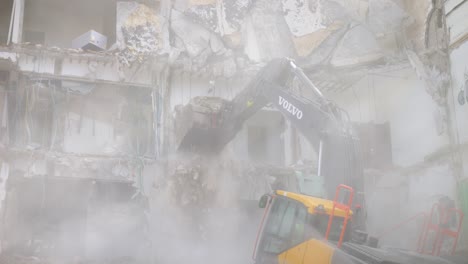 A-dust-cloud-reduces-visibility-as-an-excavator-tears-down-a-concrete-building