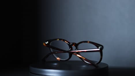 brown-and-green-tortoiseshell-round-prescription-glasses-rotating-360-degrees-against-a-black-background