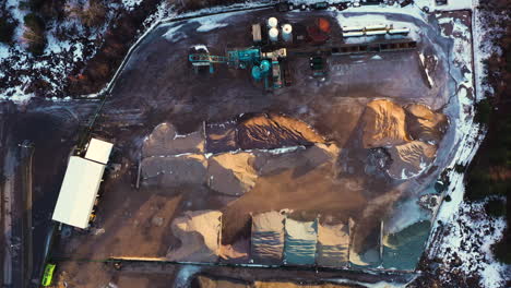Cement-factory-machinery-with-gravel-piles-in-aerial-top-down-view