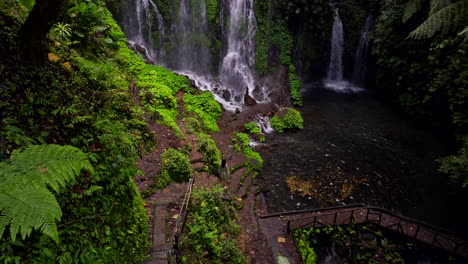 Back-view-of-woman-standing-and-admiring-natural-pool-of-Banyu-Wana-Amertha-Waterfall,-exotic-location-in-Bali-in-Indonesia