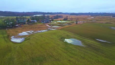 Aerial-drone-shot-over-snow-melting-over-meadow-on-an-early-spring-morning-along-rural-countryside