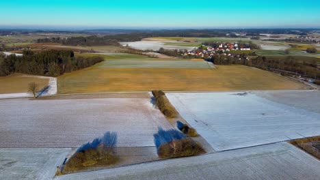 Campos-Bañados-Por-El-Sol-Iluminados-Por-El-Hielo-Con-Un-Pueblo-A-Lo-Lejos