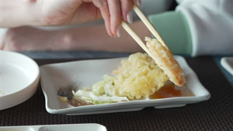 A-woman-with-chopsticks-in-hand-takes-thin-slices-japanese-vegetable-tempura-recipe-with-ginger-ponzu-sauce-Healthy-vegetarian-food