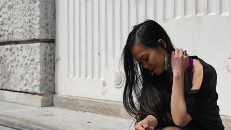 Young-Asian-woman-on-stone-bench-scratches-her-neck-and-smiles