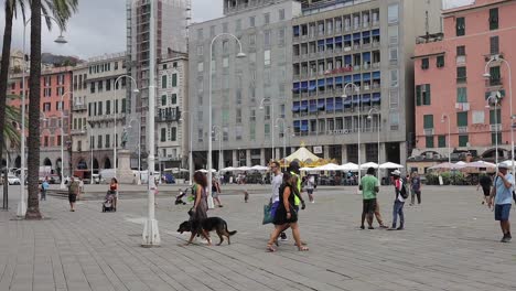 Slow-motion-clip-of-people-walking-through-town-square-at-old-Genoa-Port,-Porto-Antico,-in-Italy