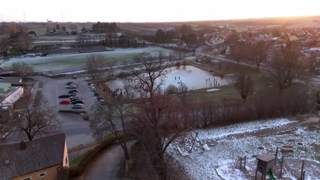 Aerial-View-Of-Frozen-Lake-With-Ice-Skaters-On-The-Ice---Drone-Shot
