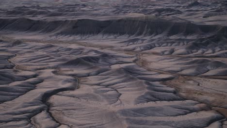 Heavily-eroded-cracked-dry-desert-landscape-with-soft-blue-hues-on-barren-ground-in-Hanksville-Utah