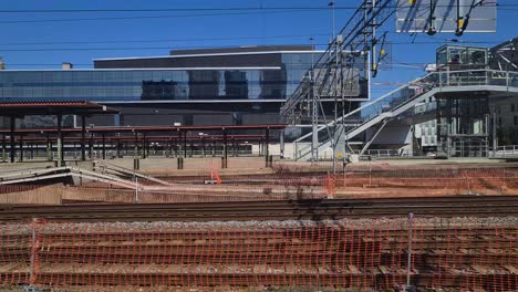 Zug-Verlässt-Oslo,-Norwegens-Hauptbahnhof,-Passagier-Sicht-Auf-Moderne-Zentrale-Gebäude-Und-Bahngleise-An-Einem-Sonnigen-Tag