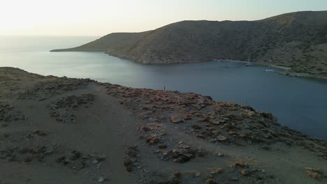 Lone-drone-pilot-standing-on-island-ridge-near-sun-lit-ocean