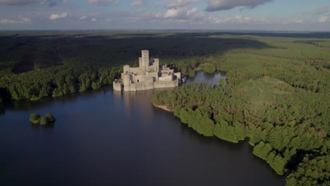 Aerial-dolly-shot-of-the-beautiful-Castle-of-Stobnica,-Poland---a-big-tourist-attraction-built-on-an-artificial-island-on-a-lake-in-the-middle-of-an-unhabituated-forest