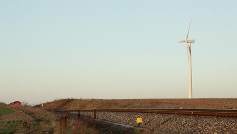 Red-Deutsche-Bahn-freight-train-passing-by-with-a-wind-turbine-in-the-background-at-dusk