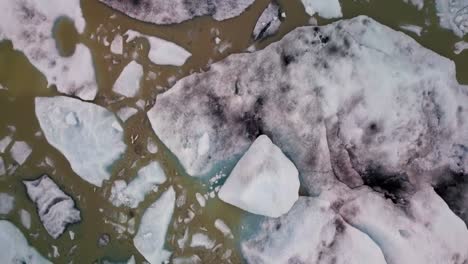 Icebergs-floating-in-muddy-glacier-lagoon-in-Iceland