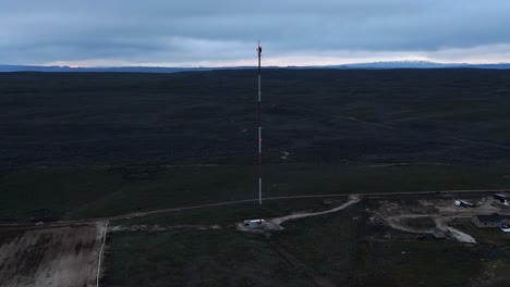 Tall-cell-phone-tower-in-barren-desert-overcast-winter-landscape-next-to-construction-site-in-late-evening