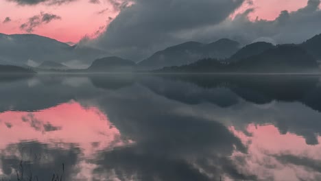 Dramatic-pink-sunset-skies-with-dark-stormy-clouds-reflected-in-the-still-water-creating-an-otherworldly-sight