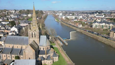 Drone-flying-over-Basilica-of-Notre-Dame-d'Avesnières-along-Mayenne-River,-Laval-in-France