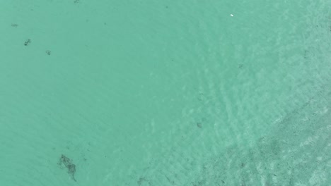 Drone-flying-over-turquoise-and-shallow-sea-waters
