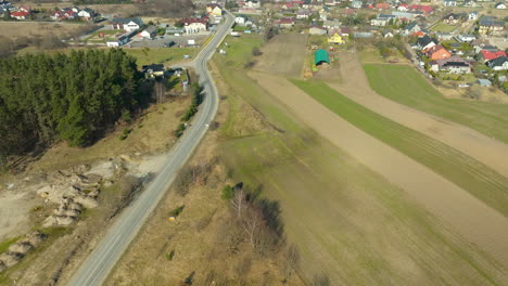 Luftaufnahme-Einer-Straße,-Die-In-Ein-Ländliches-Dorf-Mit-Häusern-Und-Feldern-Führt