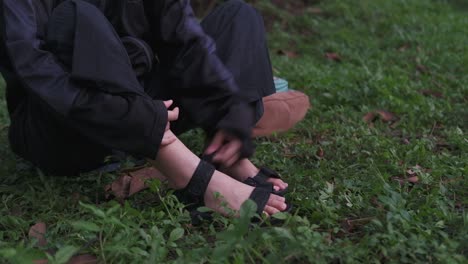 Young-woman-putting-on-Velcro-sandals-on-feet-in-outdoor-settings