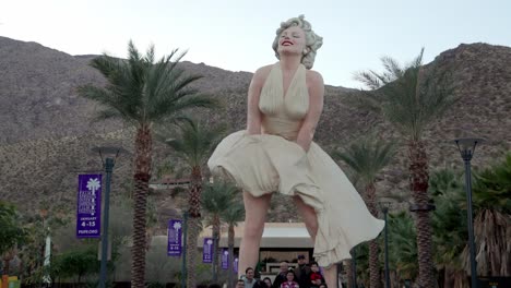 Marilyn-Monroe-statue-in-Palm-Springs,-California-with-people-below-and-gimbal-video-walking-forward