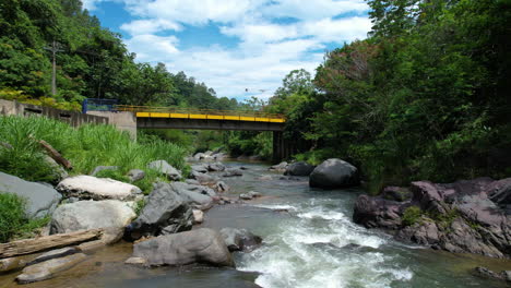 Slow-flyover-rocky-Jimenoa-River-with-bridge-on-Tropical-landscape
