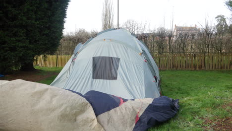 Ein-Reifer-Mann,-Der-Auf-Einem-Campingplatz-Ein-Zelt-Abbaut-Und-Die-Außenplane-Aus-Dem-Gras-Entfernt