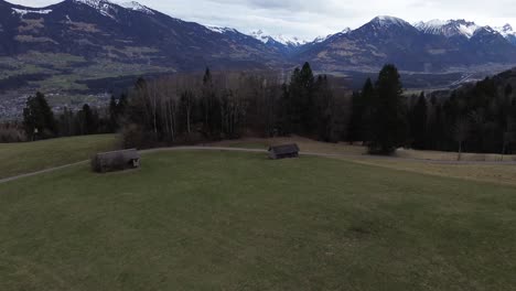 Drone-Inclinado-Hacia-El-Bosque-De-Pinos-Y-Montañas-Cubiertas-De-Nieve,-Vista-Aérea-Del-Paisaje-Urbano-Sobre-Nenzing-Austria