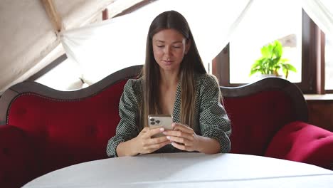 Young-happy-woman-sitting-alone-with-a-smartphone-looking-happy
