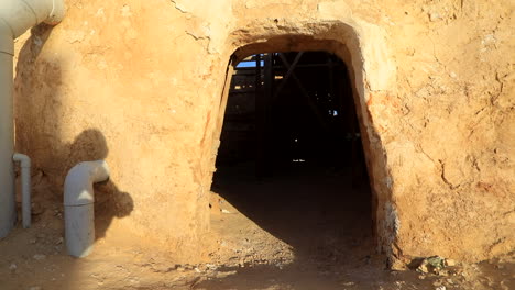 Sunlit-view-of-Star-Wars-filming-location,-desert-cave-entrance-with-pipes,-clear-sky