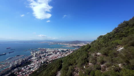 Aerial-Drone-Fly-above-coastal-mediterranean-village-at-Strait-of-Gibraltar-blue-skyline-and-green-hills,-establishing-panoramic-daylight-sea-beach-landscape