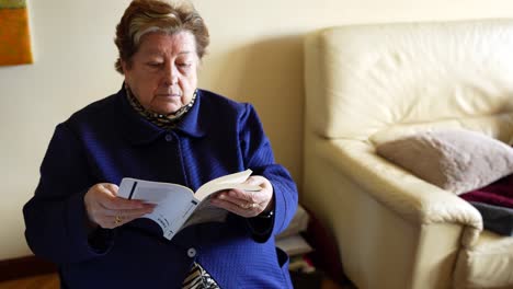 Old-adult-woman-finishing-reading-a-book-at-home