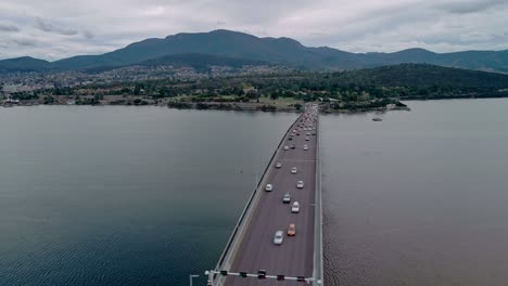 Parallax-Drohnenaufnahme-Einer-Brücke-Mit-Darauf-Fahrenden-Fahrzeugen-über-Einem-Fluss