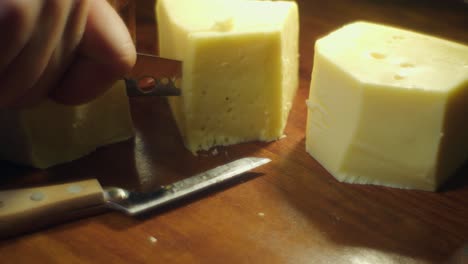 Soft-focus-closeup:-Glowing-cheese-on-cutting-board-sliced-with-knife