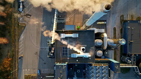 Top-down-drone-shot-above-a-smoking-power-plant,-during-a-sunny-evening