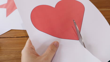 Close-up-of-hands-cutting-heart-shape-on-paper-using-scissors