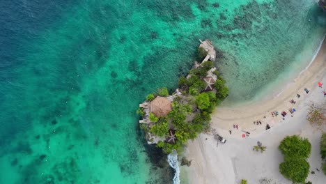 Top-down-drone-footage-of-a-white-beach-with-tourists-and-turquoise-water-on-Siquijor-in-the-Philippines,-reverse-way
