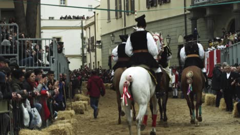 Su-Componidori-horse-riding-at-the-Sartiglia-feast-and-parade,-Oristano-carnival,-Sardinia,-Italy-Riders-on-horses-ride-past-the-audience-in-slow-motion