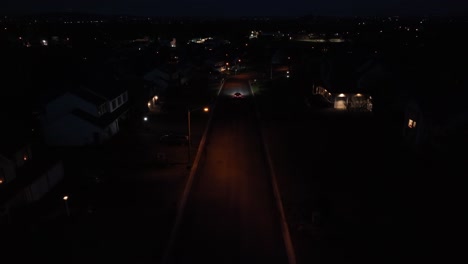 Car-driving-through-dark-American-neighborhood-at-night