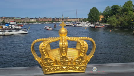 Gilded-Crown-on-Skeppsholmsbron,-Bridge-and-Bay-of-Stockholm,-Sweden-on-Sunny-Day
