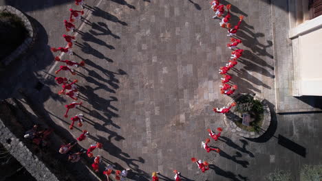 Top-Down-Aerial-View-of-Majorettes-in-Red-Uniforms,-Girls-Performing-Group-Practicing-Choreography,-High-Angle-Drone-Shot