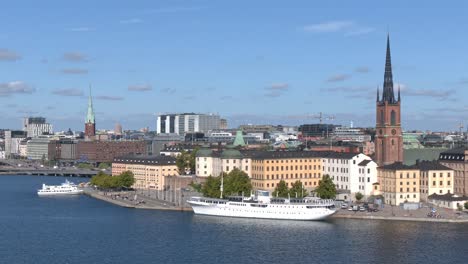 Vista-General-Del-Casco-Antiguo-De-Estocolmo,-Incluidos-Algunos-Barcos,-El-Puerto-Y-La-Torre-De-La-Iglesia-De-Riddarholmen