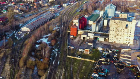 Industrial-area-with-grain-storage-silos-and-railway-station-and-tracks-next-to-it,-aerial