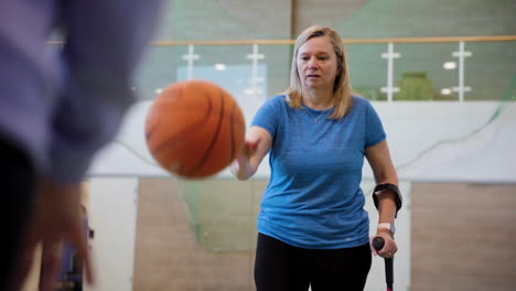 Woman-using-crutches-while-dribbling-a-basketball-around-opponent