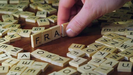 A-Partir-De-Una-Variedad-De-Mosaicos-De-Letras-De-Scrabble,-Se-Hace-Fraude-De-Palabras-En-Una-Mesa-De-Madera