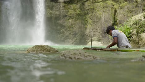 Philippines-waterfalls-landscape-closeup-Camugao-falls-man-fishing-at-southeast-asia-water-falling-background-asian-boy-activity-capturing-marine-wildlife-in-turquoise-water-between-rock-cliff