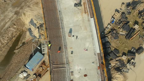Top-down-panning-shot-of-construction-site-with-worker,-build-new-road-in-summer