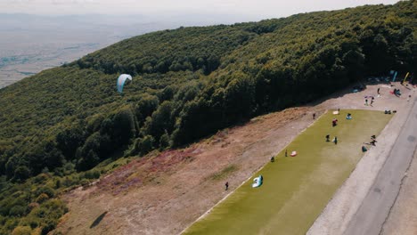 Drone-shot-of-a-paraglider-taking-of-from-a-start-at-the-side-of-a-mountain