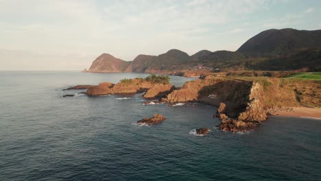 Aerial-drone-fly-above-blue-peninsula-of-Kyotango-Kyoto-Japan-Travel-landscape-sea-water-floating-slowly-in-Panoramic-clean-environment,-mountain-range-background