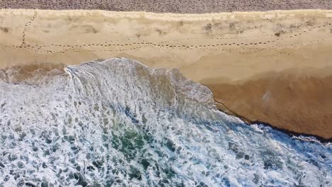 Waves-break-onto-golden-sandy-beach-during-sunset-in-Baja-California-Sur,-Mexico