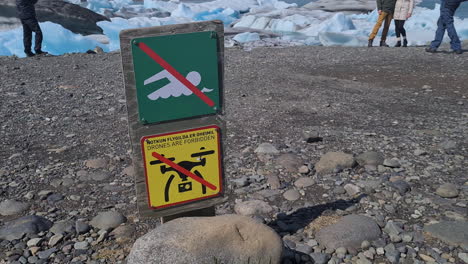 Drones-are-Forbidden-and-No-Swimming-Signs-in-Front-of-People-Taking-Pictures-on-Jokulsarlon-Glacial-Lagoon,-Iceland