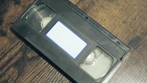 Hände-Kleben-Ein-Leeres-Etikett-Auf-Die-Vorderseite-Einer-Alten-VHS-Kassette